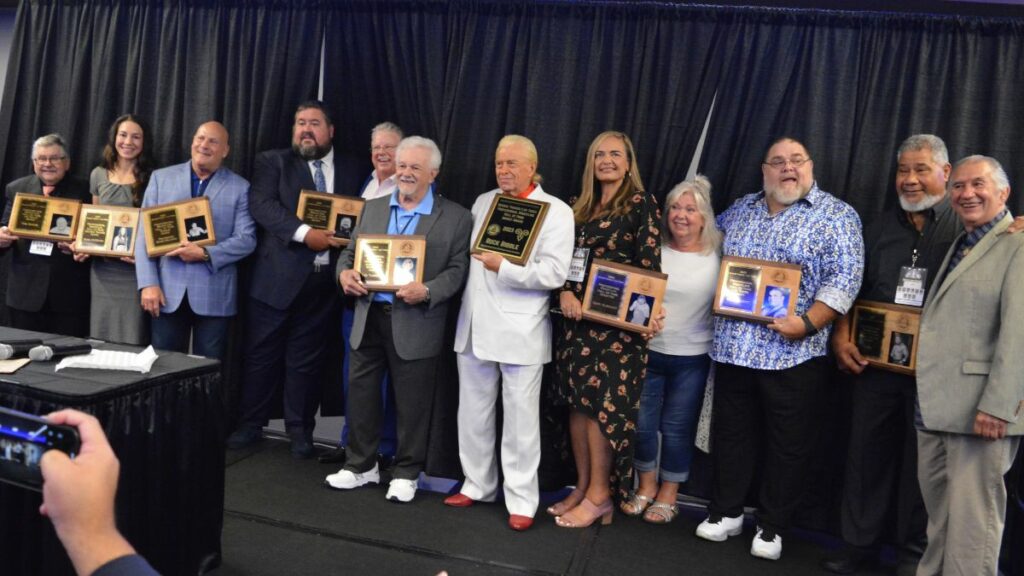 The Class of 2023 at the Tragos/Thesz Professional Wrestling Hall of Fame induction on Saturday, July 22, 2023, in Waterloo, Iowa. Left to right: Tom Burke, Sara McMann, Jody Simon representing Boris Malenko, Conrad Thompson and his presented Bruce Prichard, Les Thatcher, Rock Riddle, Monica Anoa'i-Albright and Patti Albright representing Gary Albright, Bill DeMott, Haku and Jerry Brisco. Photo by Joyce Paustian