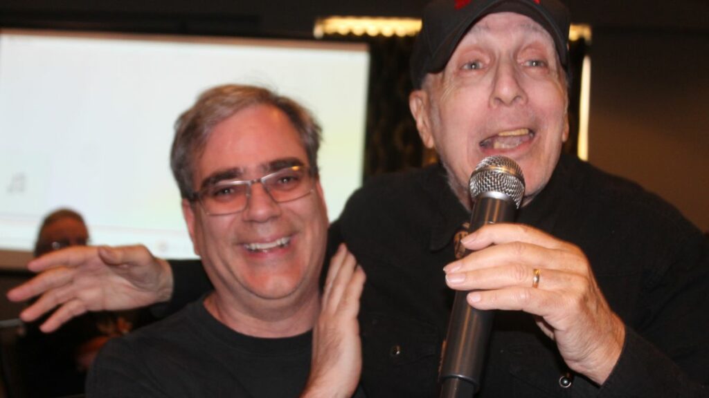 Bill Apter sings while in the lap of Greg Oliver on Friday, May 17, 2024. Photo by Debrah Miceli