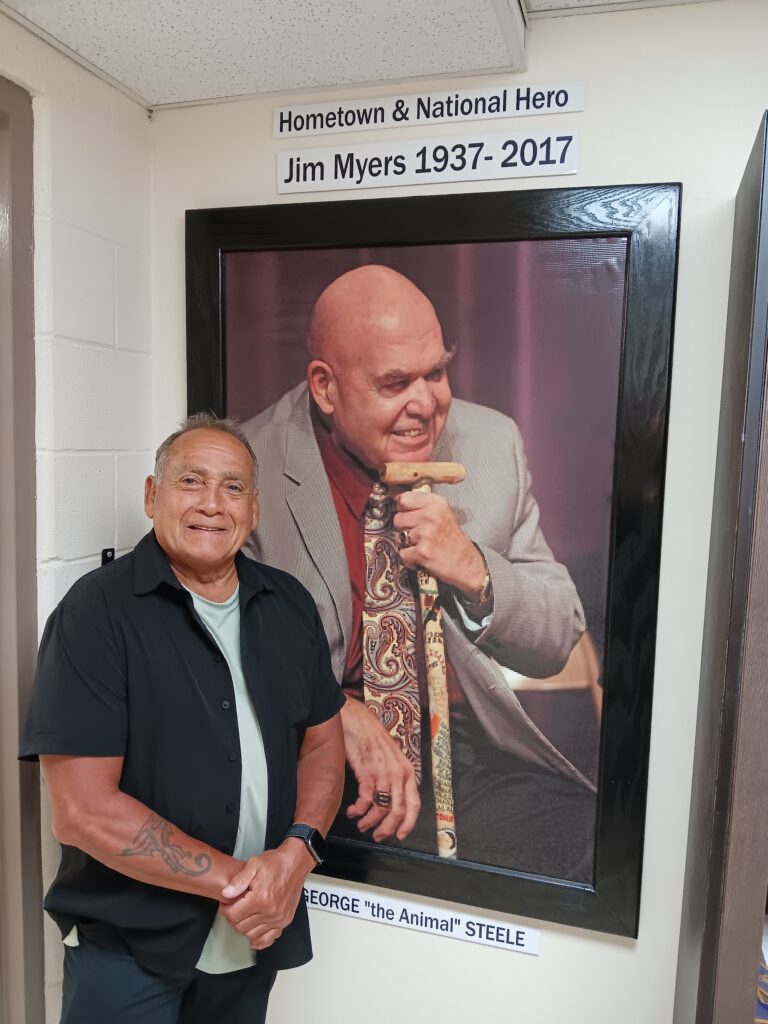 Berney Gonzales in front of a photograph of his coach Jim Myers.