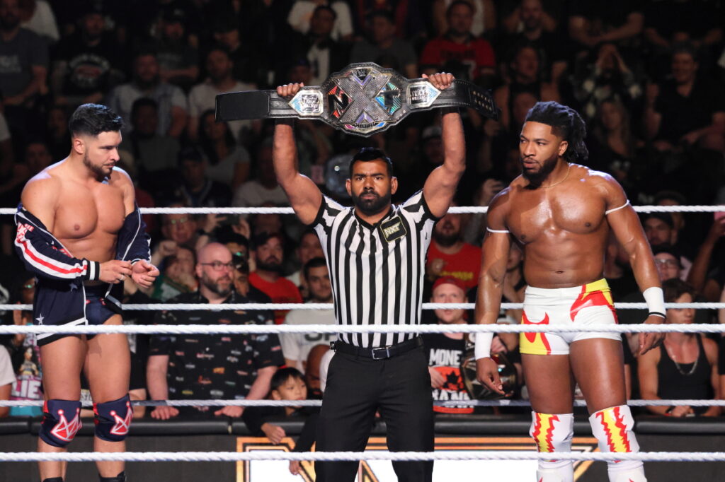 NXT head referee Darryl Sharma, with Ethan Page and Trick Williams looking on, holds up the NXT Championship belt ahead of the Fatal 4-Way main event at NXT Heatwave on Sunday, July 7, 2024, at Scotiabank Arena in Toronto. Photo by Steve Argintaru, Twitter/IG: @stevetsn