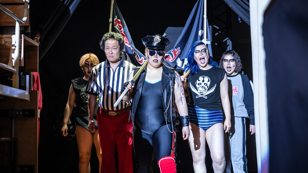 Yuriyan Retriever as Kaoru “Dump” Matsumoto with referee Shiro Abe and The Extreme Evil Alliance (Bull Nakano, Condor Saito, and Bison Kimura) in The Queen of Villains. Netflix photo