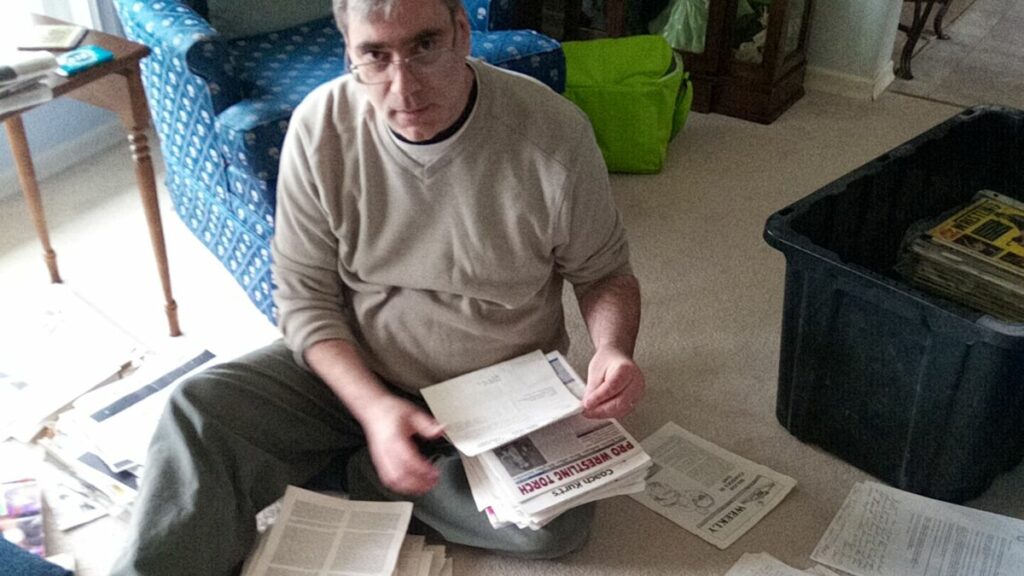 Greg Oliver sorts through one bin of wrestling stuff gotten from the late Terry Dart. Photo by Jim Oliver